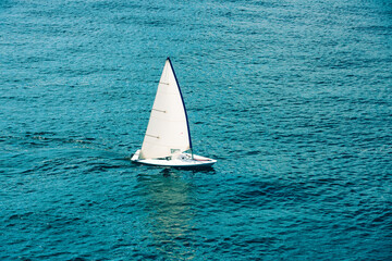 Sailing boat in open sea at sunlight. White sail on blue water. Luxury yacht in the ocean. Aerial view of Regatta sailing