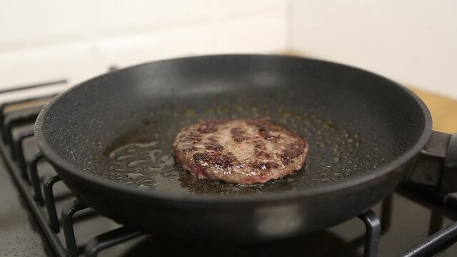 Burge beef patty frying on hot pan at home kitchen in close up.Fresh raw beefsteak meat being fried for dinner in closeup.Video clip of delicious natural minced pork cooking in oil