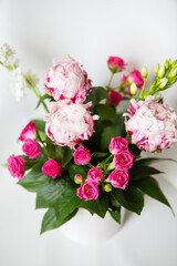 A beautiful bouquet of tender pink peonies and small roses stands on a white chair. Suitable for bridal bouquet, birthday.