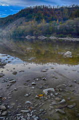 Beautiful landscape with high mountains with illuminated peaks, stones in mountain lake, reflection, blue sky and sunrise. HDR