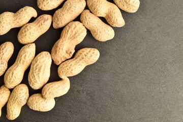 Unshelled organic peanuts, close-up, on a slate board.