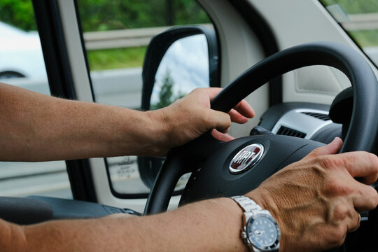 Mainz, Germany - June 20, 2019: Hands of a man in Fiat Ducato cockpit while driving.