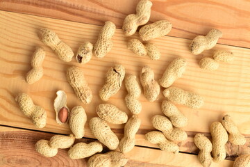 Unpeeled organic peanuts, close-up, on a wooden table.
