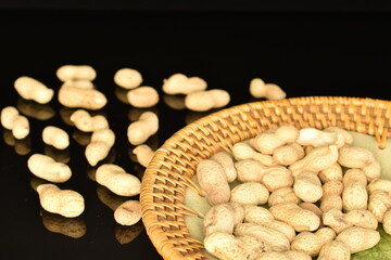 Unpeeled organic peanuts, close-up, on a black background.