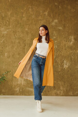 Young woman wearing stylish trendy yellow leather trench coat. Casual outfit