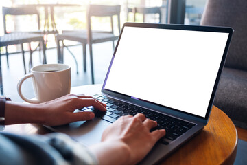 Mockup image of a woman using and typing on laptop computer keyboard with blank white desktop screen in cafe