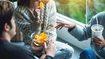 Closeup image of friends drinking and eating potato chips together