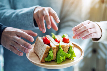 Group of people grabbing a piece of whole wheat sandwich in wooden plate to eat