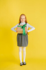 Giving and getting presents on Christmas holidays. Teen smiling girl having fun, holding big gifts isolated on yellow studio background. New Year 2021 meeting, childhood, happiness, emotions.