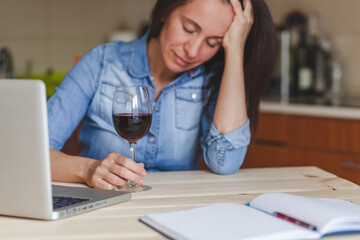 Depressed woman drinking red wine at home.