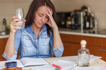 Tired mid adult woman reading textbook at home.