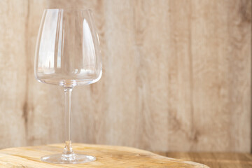 An empty glass for white or red or rose wine stands on a wooden background.