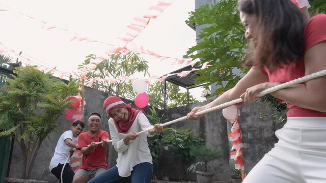 three people in one team tried to pull the rope hard during the tug-of-war competition at Indonesia's Independence Day celebrations