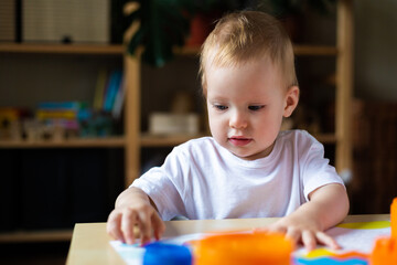 Cute little girl playing alone with many colorful toys