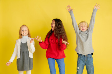 Obraz premium Laughting, smiling. Portrait of little caucasian children isolated on yellow studio background with copyspace. Beautiful teen models. Concept of human emotions, facial expression, sales, ad, youth.