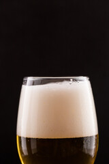 Glass with beer on a black isolated background close-up.
