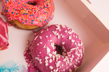 Multi-colored donuts in a white box close-up.