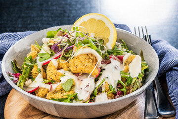 A plate of crispy Calamari Salad with lettuce, radish, lemon, tomatoes, asparagus and avocado.