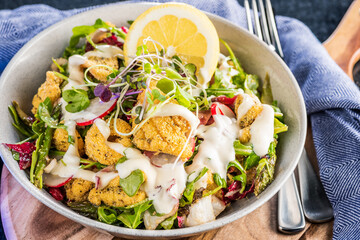 A plate of crispy Calamari Salad with lettuce, radish, lemon, tomatoes, asparagus and avocado.