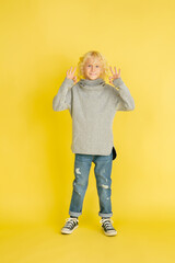 Nice signs, smiling. Portrait of little caucasian boy isolated on yellow studio background with copyspace. Beautiful model. Concept of human emotions, facial expression, sales, ad, youth.