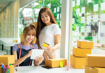 Female SME business owners and colleagues Helping to explain credit card payment to customers who...