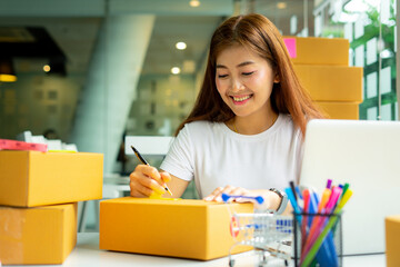 Female SME business owner talking to write And verify the customer's address in order to deliver the goods to the customer, the operator's office concept Sell ​​products online