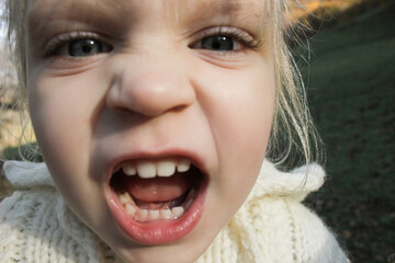 Close up portrait of cute three years old blonde girl acting goofy in front of the camera.
