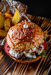 Traditional beef burger with vegetables on dark background