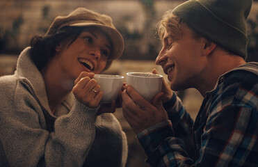 Happy young couple is drinking coffee and smiling while sitting at the cafe. Couple in love....