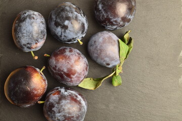 Ripe dark blue organic plums on a slate board, close-up.