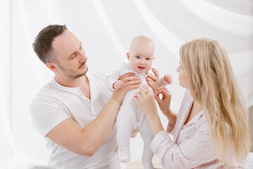 A young Caucasian family with a newborn baby daughter in the bedroom. White light home interior.