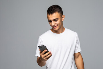 Portrait of young man use smart phone in hands, checking email, using 3G, wi-fi internet, searching contact, isolated on grey background