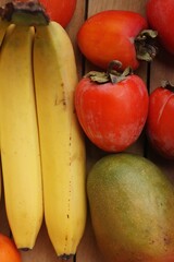 Fototapeta na wymiar Juicy persimmons bananas and mango close up 