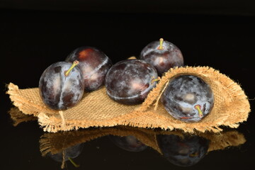 Ripe dark blue organic plums, close-up, on a black background.