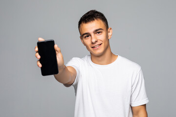 Portrait of a smiling man showing blank smartphone screen on a white background