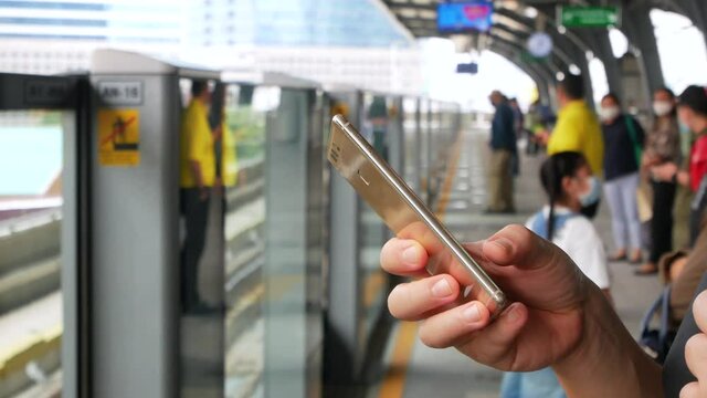 POV to hand using mobile phone waiting for skytrain approaching