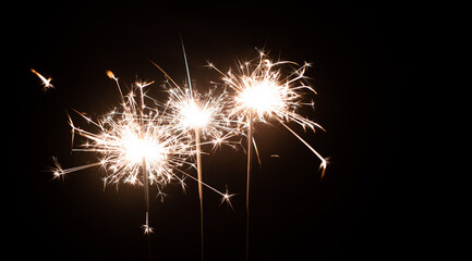 Three burning sparklers on a black background with place for text