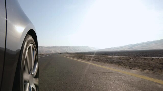 Car Wheel Perspective, passes over White and Yellow Zebra Crossing and Speeds off into the Desert