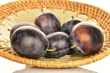 Ripe dark blue organic plums, close-up, on a ceramic plate.