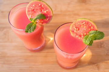 Directly above shot of glass of organic Guava juice with fresh guava on wooden table