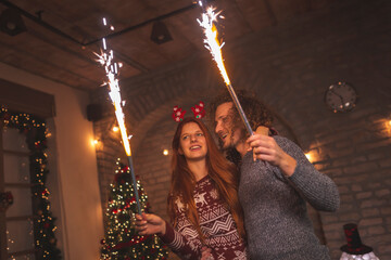 Fototapeta na wymiar Couple holding sparklers for Christmas Eve