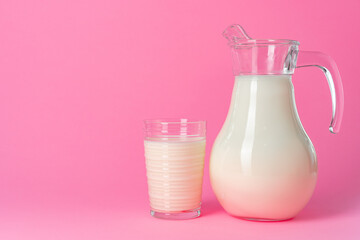 Glassware with fresh milk against pink pastel background