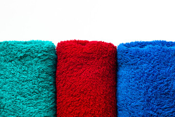 Towels of three colors on a white background. Red green and blue.