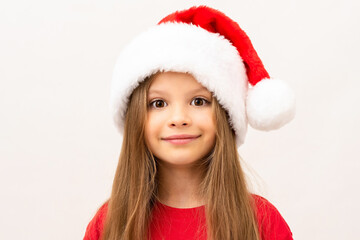 A little girl posing on a white background in a Christmas hat.