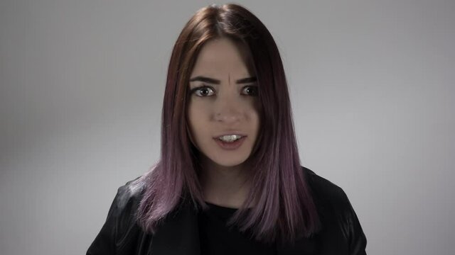 Portrait of a young lady saying no in slow motion on the white background. She disagrees with something shaking head. Attractive caucasian lady is expressing a rejection. Concept of person's emotions.