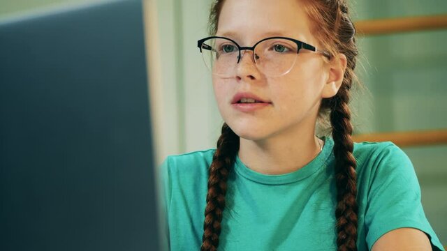 Teenage girl in glasses is talking during her online class