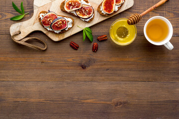 Toasted bread with figs, ricotta and honey on wooden cutting board