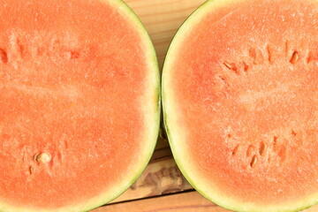 Sliced red organic watermelon, close-up, on a wooden table.