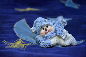 little snowman christmas decoration made of ceramics on a blue background close-up