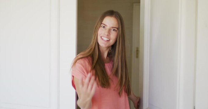 Portrait of caucasian woman opening house front to welcome people in